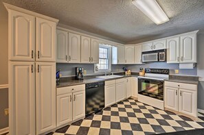 A kitchen with white cabinets, a black and white checkered floor, a dishwasher, a microwave, and a stove. - Serene Blue Ridge Getaway in Galax w/ Yard! (Galax)