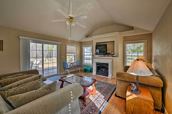 A spacious living room with a fireplace, a ceiling fan, and a television. - Serene Blue Ridge Getaway in Galax w/ Yard! (Galax)