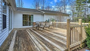 En træterrasse med spiseplads og udsigt til huset.
