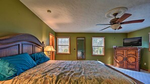Une chambre à coucher avec un grand lit, un ventilateur de plafond, une télévision et un meuble.