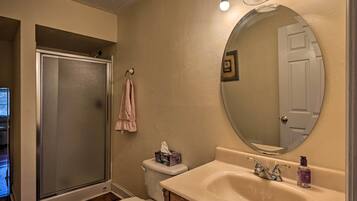 A bathroom with a shower, toilet, sink, and a large mirror.