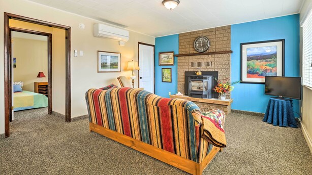 Una habitación acogedora con sofá, chimenea, televisor y una puerta que da a otra habitación.