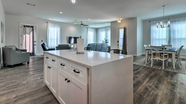 A spacious living area with a central island, a dining table with chairs, a sofa, and a television. - Spacious Gulfport Home - Walk to Beach! (Gulfport)