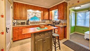 A kitchen with wooden cabinets, a granite countertop, a built-in stove, and a window with blinds. - Whimsical Lancaster House w/ Porch Near Amish Farm (Lancaster)