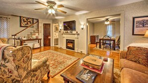A spacious living room with a fireplace, a dining area, and a staircase leading to another level. - Whimsical Lancaster House w/ Porch Near Amish Farm (Lancaster)