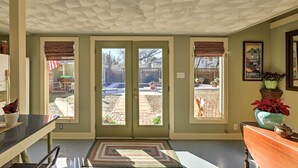 Una stanza con un soffitto decorato, una porta che dà su un patio e un'area pranzo con tavolo e sedie.