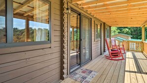 A wooden deck with a covered area, sliding glass doors, and a rocking chair. - Grill & River Access: Tiny Cabin in Sparta! (Sparta)
