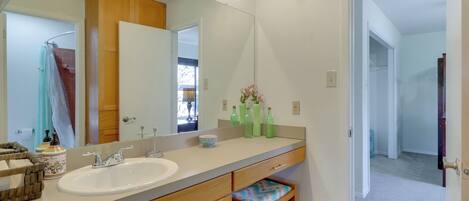 A bathroom with a large mirror, wooden cabinets, a sink, and a shower area.