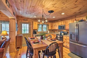 A wooden cabin interior with a dining table set for four, a refrigerator, a microwave, and a coffee maker. - Waynesville Escape - Mtn Cabin Above the Clouds! (Waynesville)