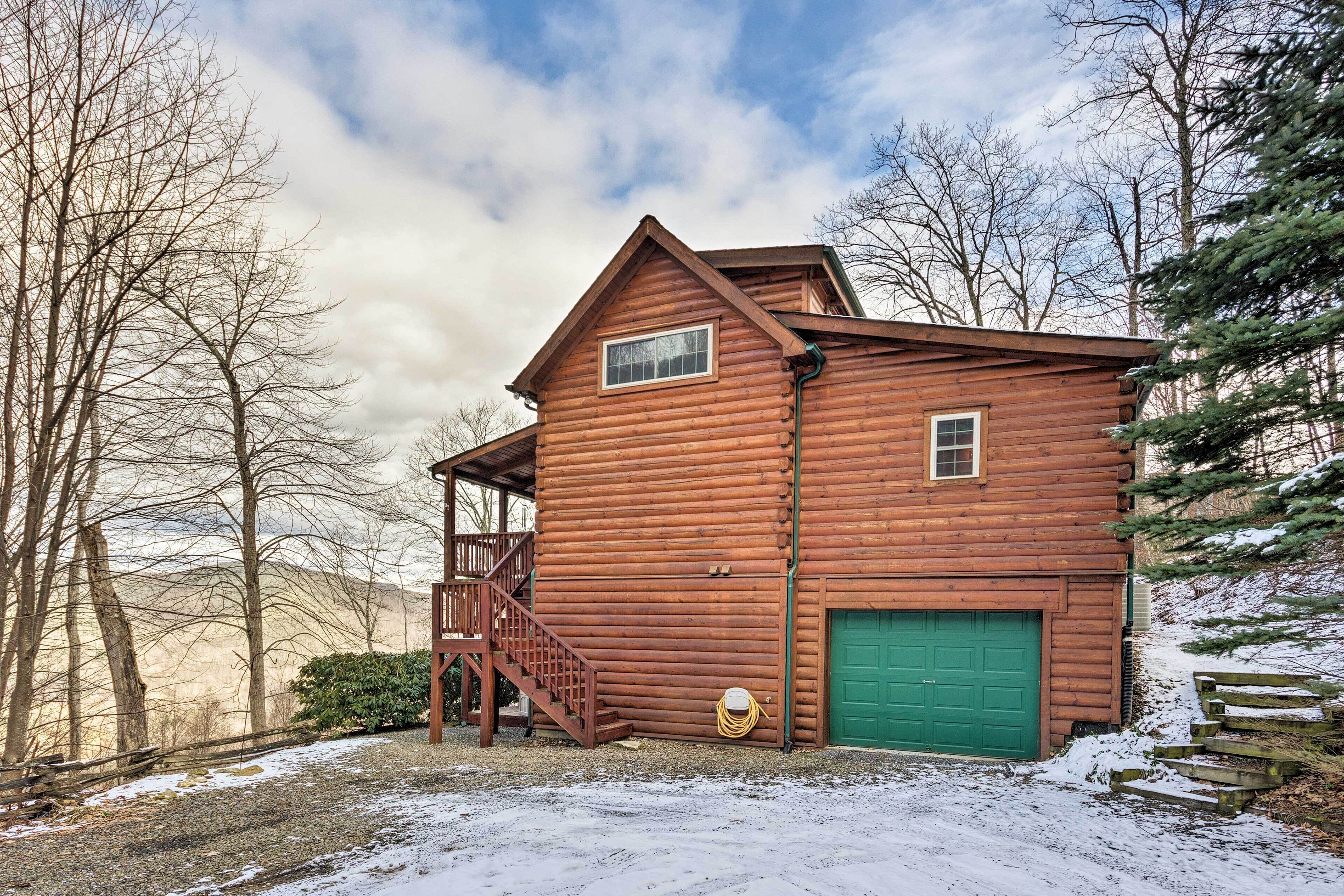 A wooden cabin with a green garage door, a small window, and a staircase leading to a deck.