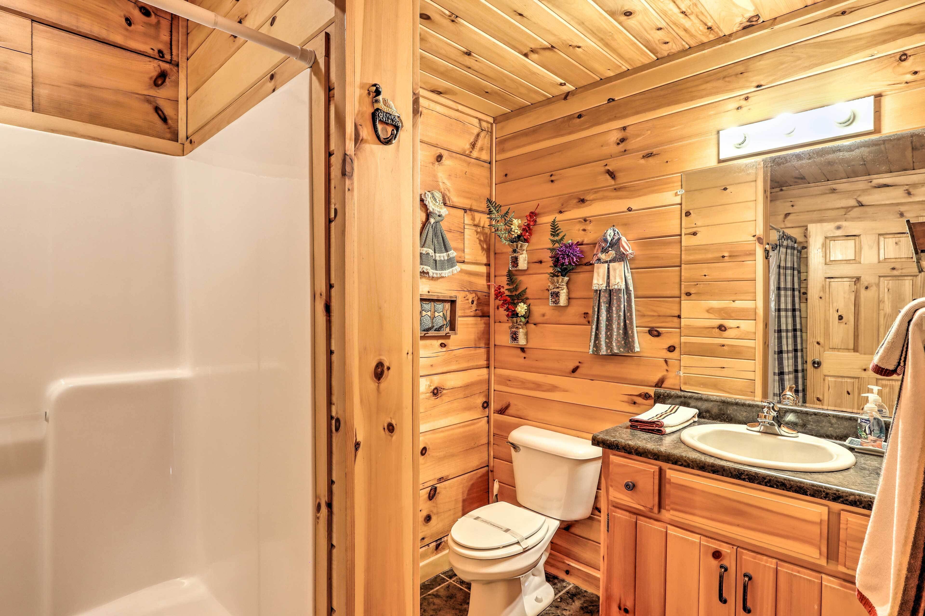 A wooden cabin bathroom with a toilet, sink, and mirror.