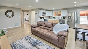 A modern living room with a brown leather sofa, a dining table, and a kitchen in the background. - On-site Boat Launch: Gun Barrel City Lake House (Mabank)