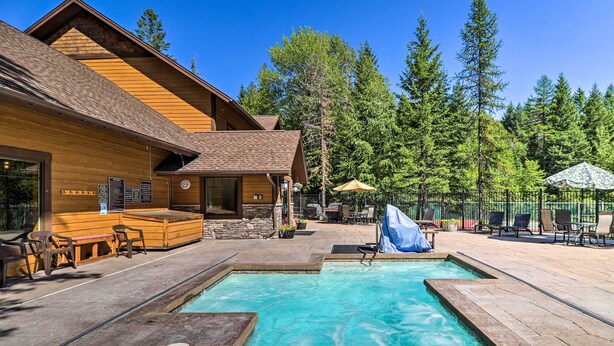 A wooden cabin with a pool, outdoor seating, and a forest backdrop. - Whitefish Escape w/ Deck: 3 Mi to Ski Resort! (Whitefish)