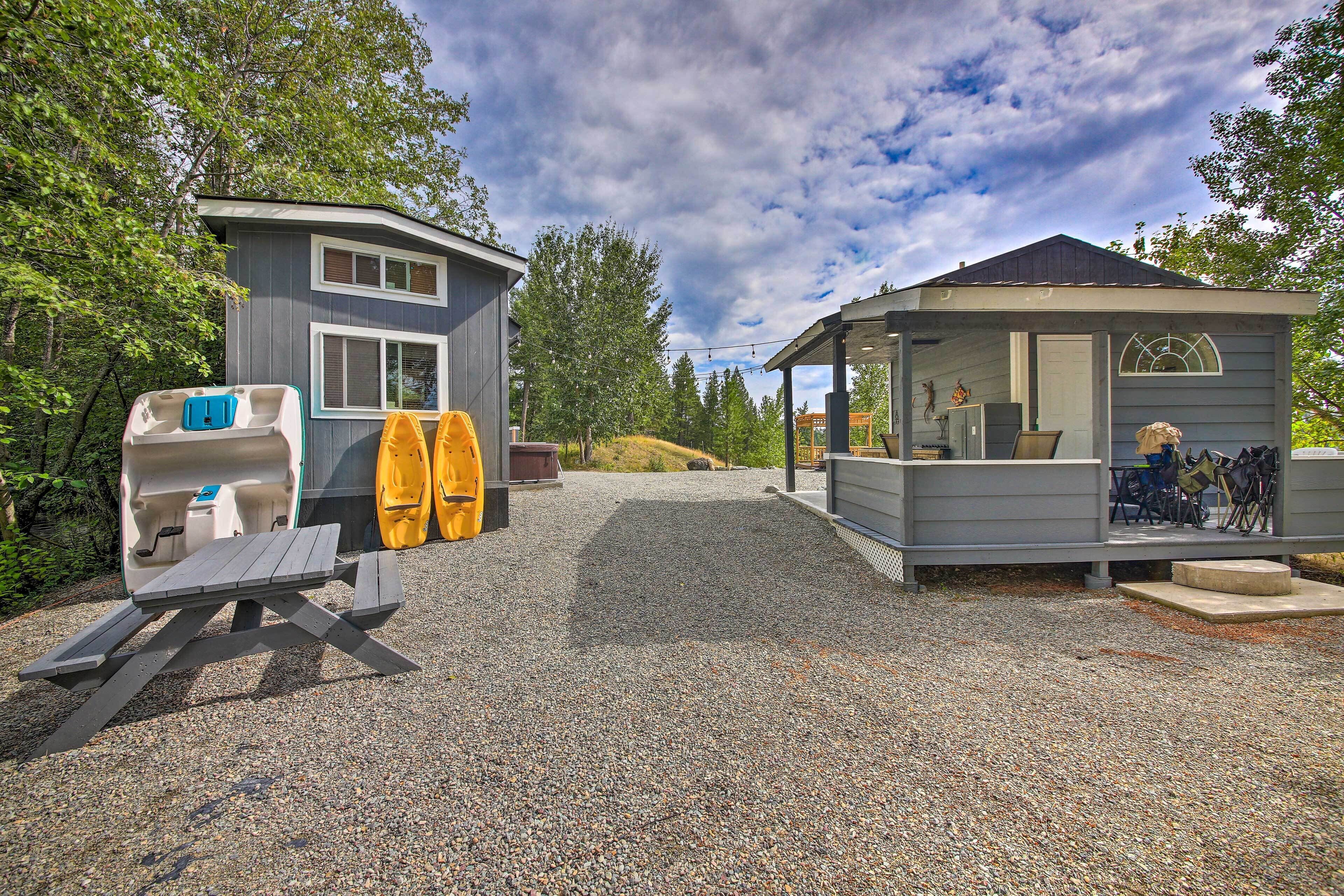 A small cabin with a covered porch, a picnic table, and kayaks stored outside.