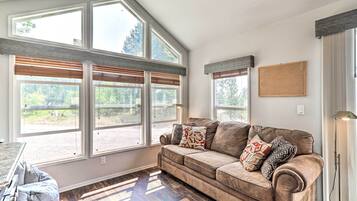 A cozy living room with a large window, a brown sofa, and a floor lamp.