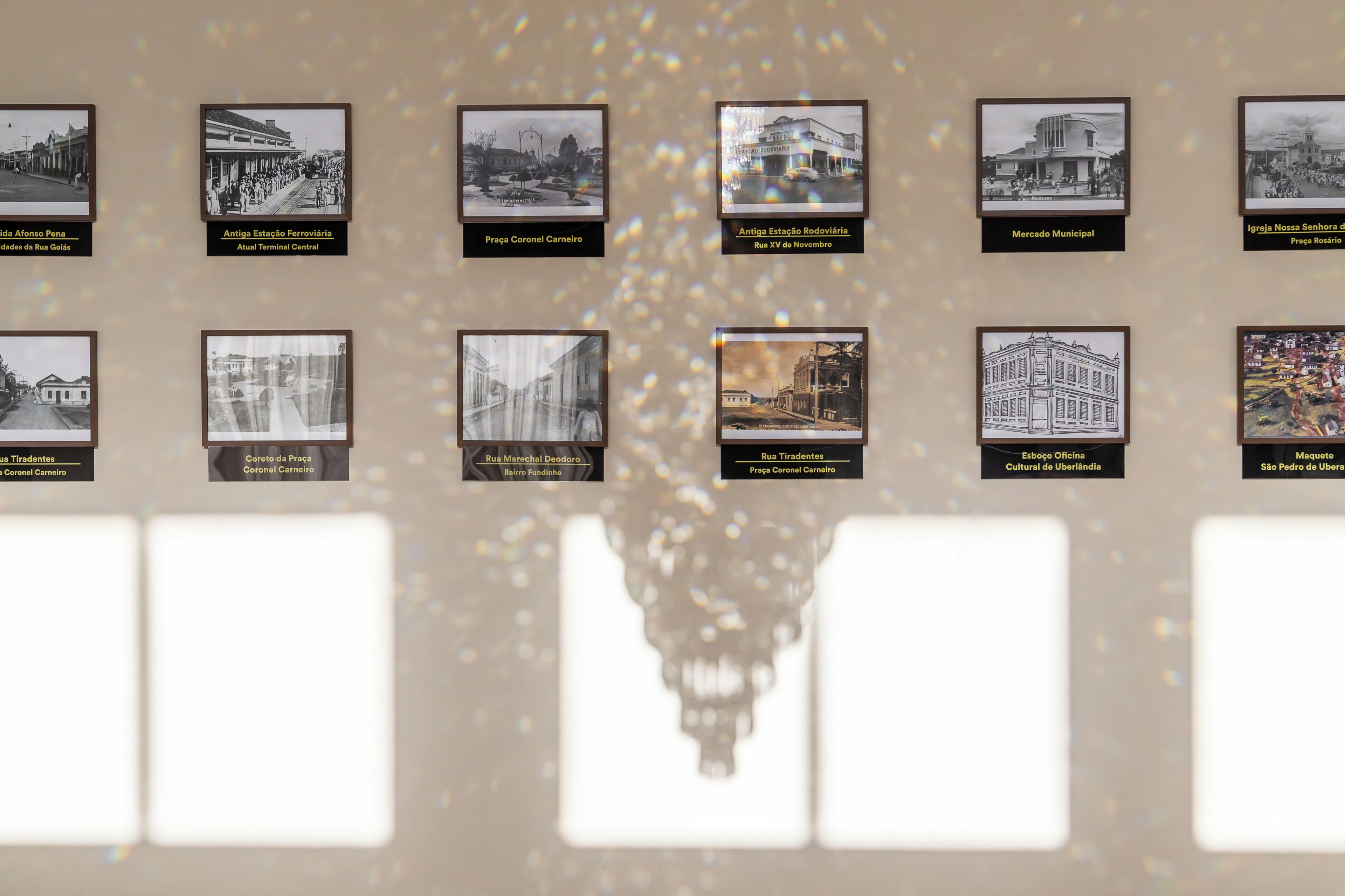 A wall of framed historical photographs with labels, depicting various buildings and scenes from a city.