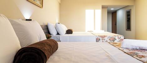 Habitación de hotel con cama, sofá, manta marrón enrollada y un cuadro en la pared.