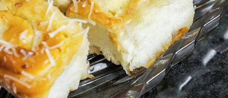 A glass dish with several pieces of bread topped with cheese and shredded coconut.