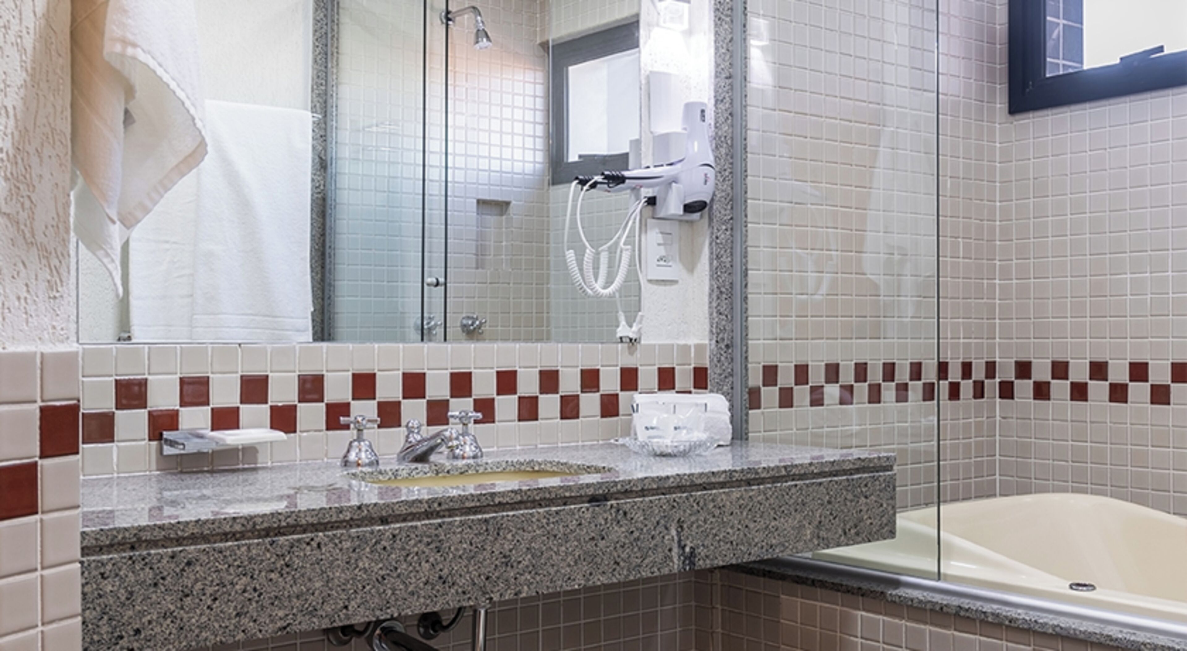 A bathroom with a granite countertop, a white sink, a mirror, a shower, and a bathtub.
