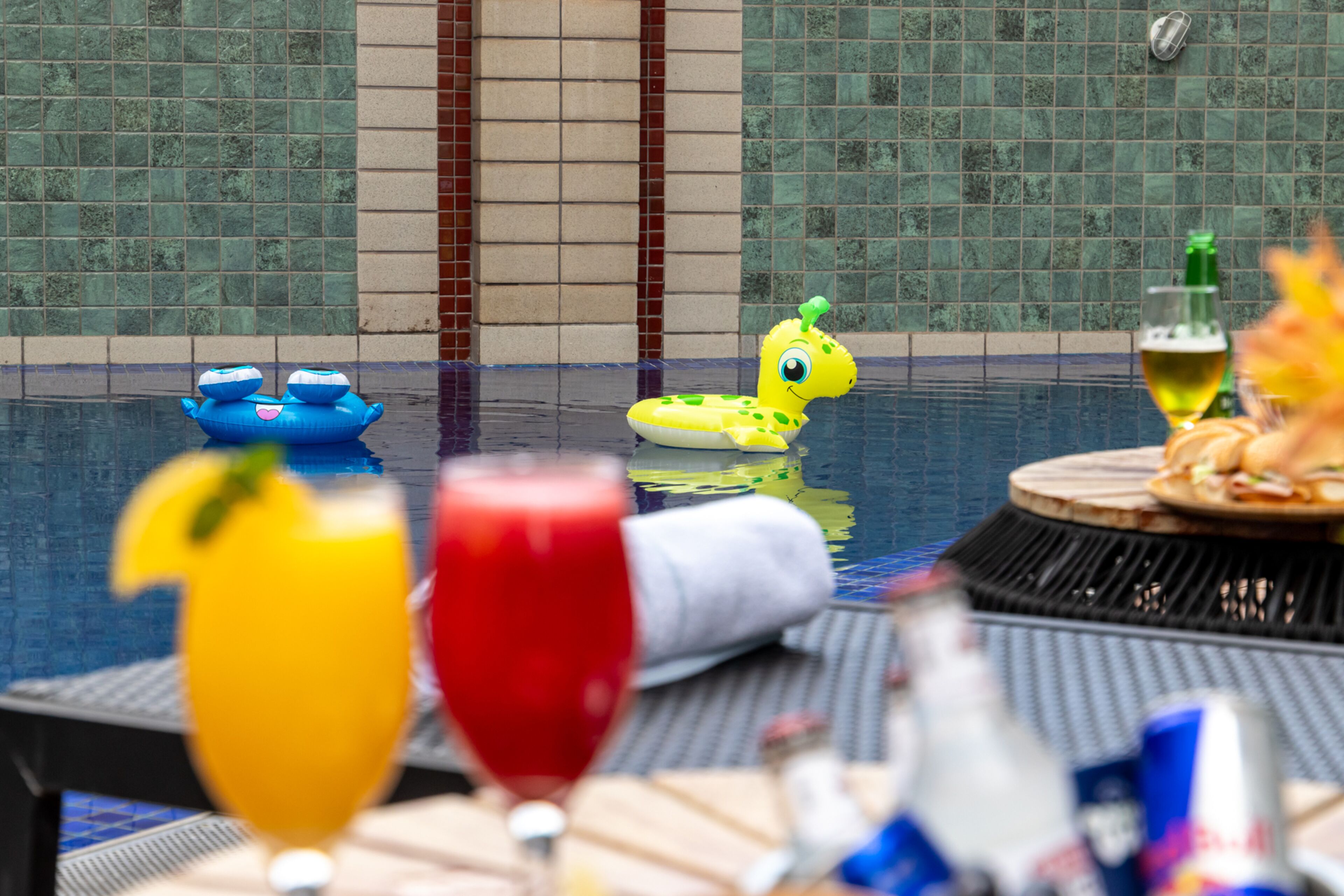 Zona junto a la piscina con una mesa de comedor, bebidas y juguetes inflables.