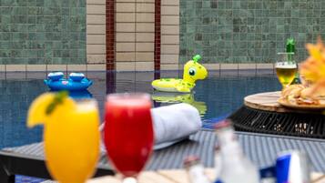 Zona junto a la piscina con una mesa de comedor, bebidas y juguetes inflables.