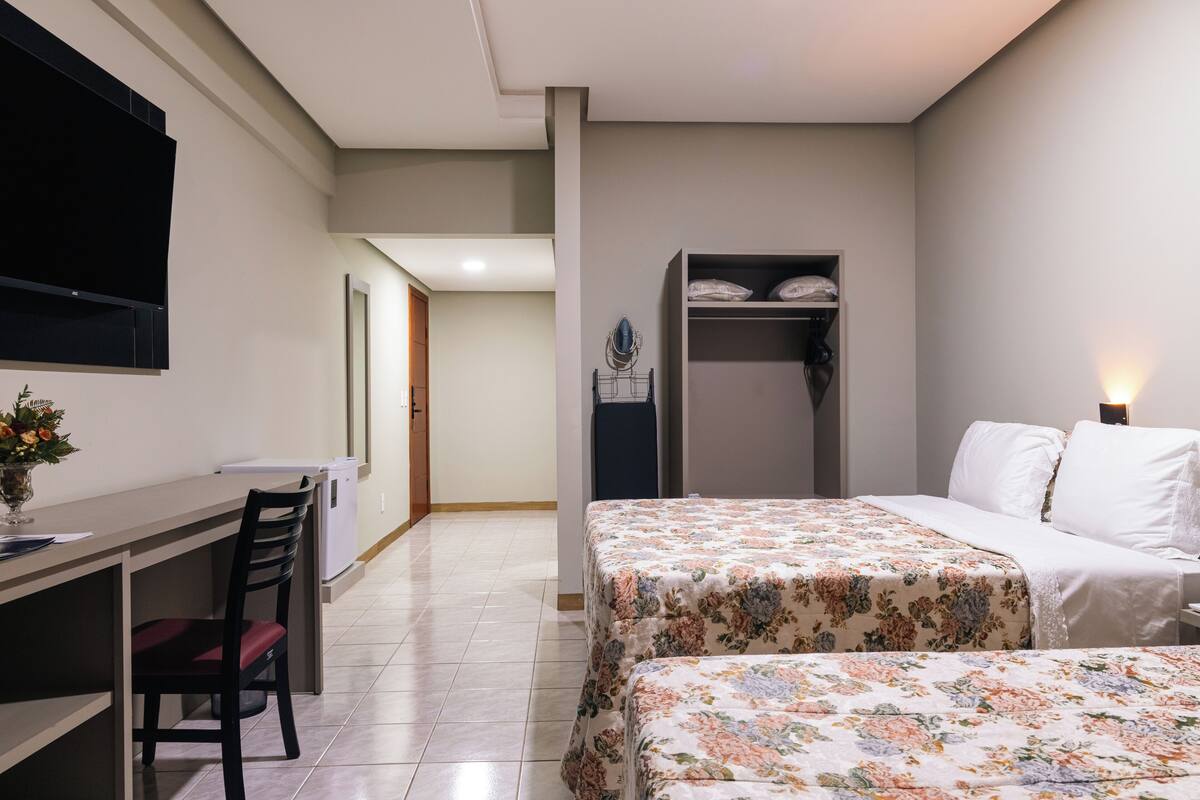 Een hotelkamer met een bed, een bureau, een stoel en een kledingkast.