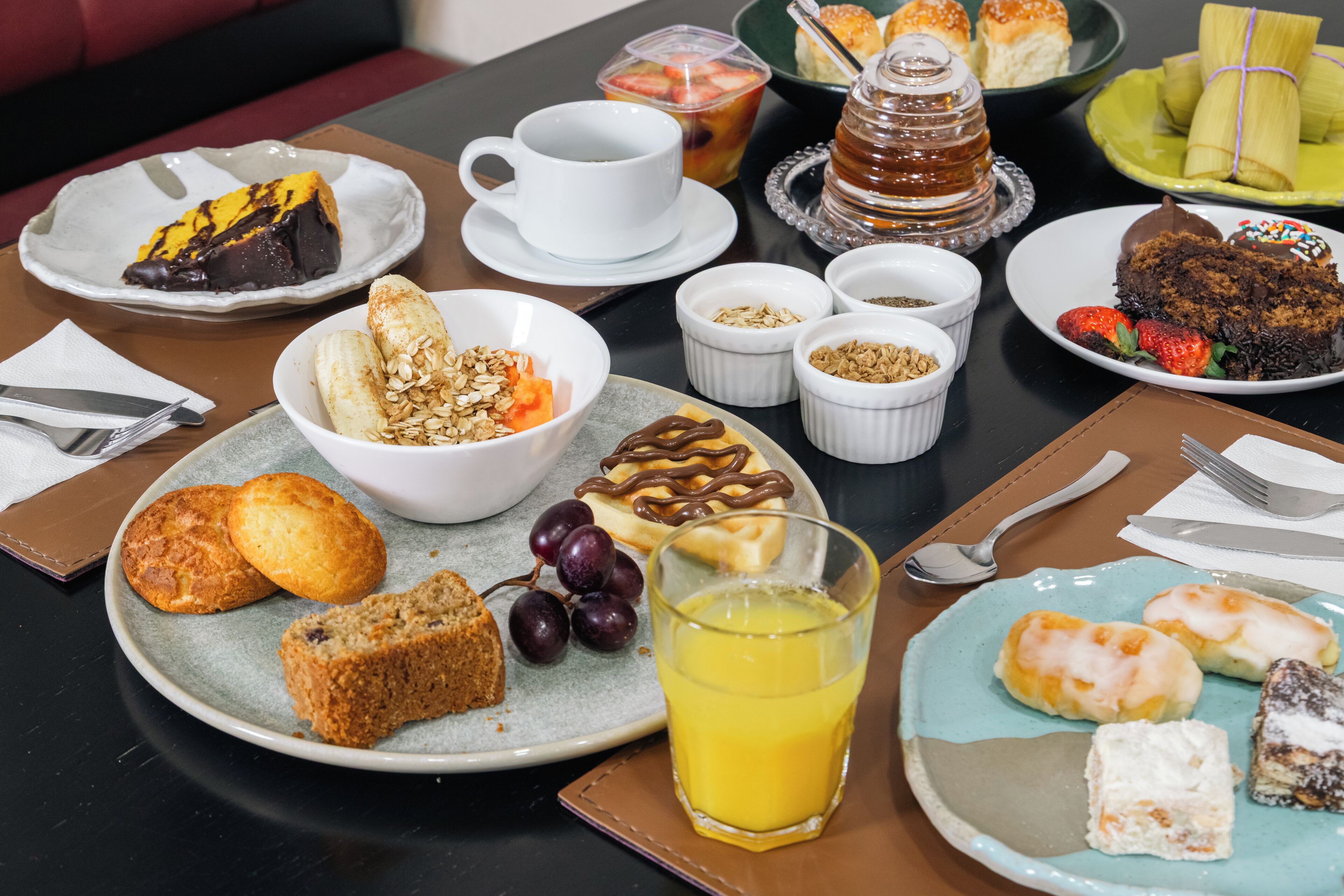 A breakfast table with various dishes including pastries, fruits, and a glass of orange juice.