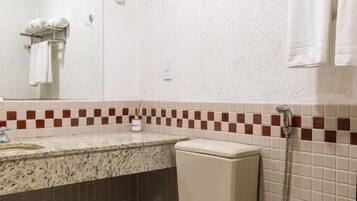 Un baño con inodoro, bidé, espejo y toallero.