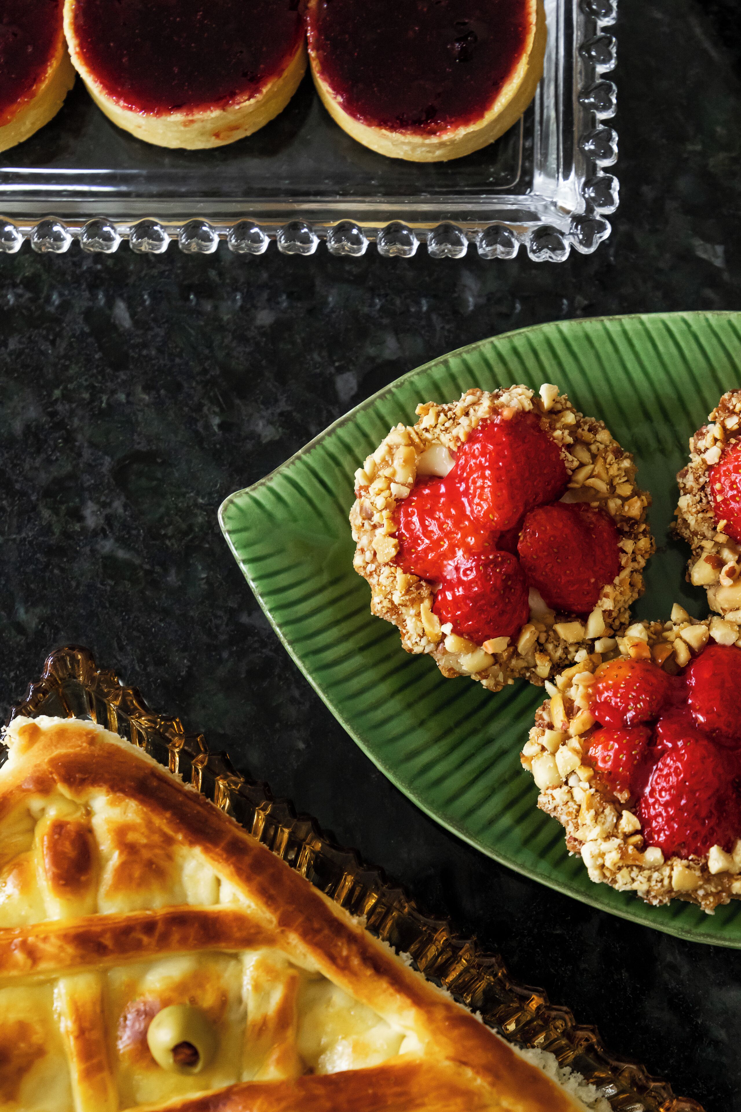 A tray of desserts, including a tart and a plate with fruit-topped cookies.