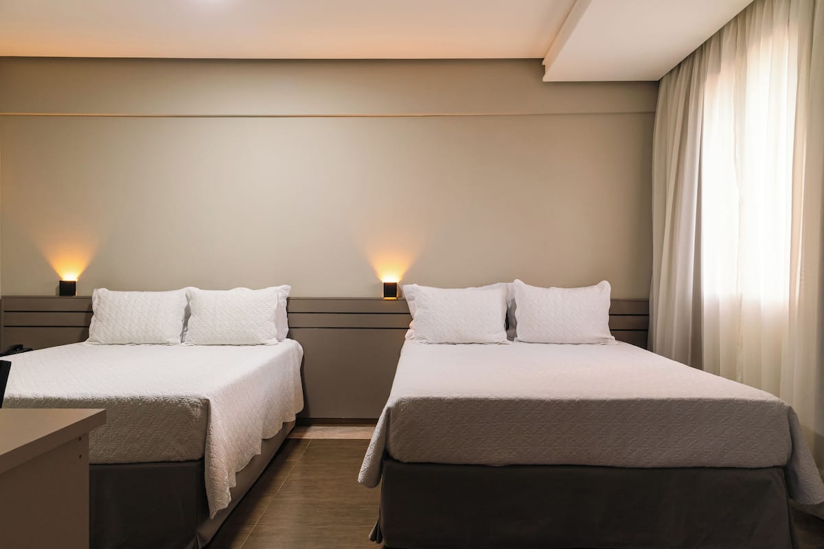 Een hotelkamer met twee enkele bedden, een bureau en een nachtkastje met lampen.