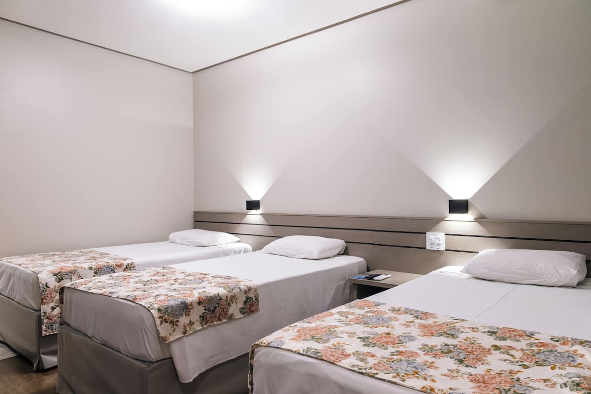 Een hotelkamer met twee eenpersoonsbedden, elk voorzien van een bloemenprint beddeken en een nachtkastje.