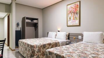 Habitación de hotel con dos camas, un armario, un cuadro y un escritorio con silla.