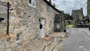 Ein Steinhaus mit traditioneller Gestaltung, einem verschlossenen Eingang und einem Turm im Hintergrund.