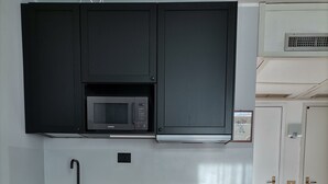 A modern kitchen with black cabinets, a microwave, a sink, and a wooden island with heart-shaped cutouts. - Le randonneur (Garessio)