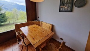 A dining area with a wooden table and chairs, a pendant light, a framed botanical print, and a wall clock. - Le randonneur (Garessio)
