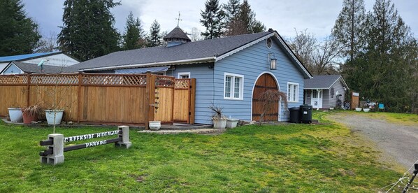 A house with a wooden fence, a sign indicating a hidden driveway, and a small porch area. - Escape to the Creekside Hideaway (Sequim)