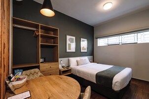 Quarto com cama, mesa de cabeceira e guarda-roupa de madeira.
