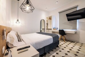 A modern hotel room with a neatly made bed, a desk with a chair, a flat-screen TV mounted on the wall, and a large mirror above the desk. - Tarata Hotel Boutique (Lima)