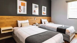 A hotel room with two beds, a wooden headboard, a bedside table with a phone, and abstract artwork on the wall. - Tarata Hotel Boutique (Lima)
