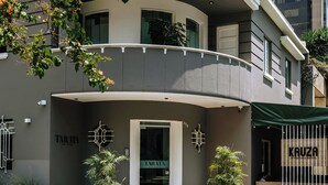 A modern building with a curved balcony, potted plants, and signage for 'TARATA' and 'Kauza'. - Tarata Hotel Boutique (Lima)