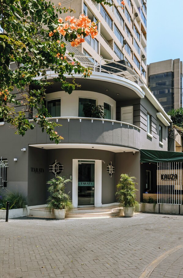 A modern building with a curved balcony, potted plants, and signage for 'TARATA' and 'Kauza'. - Tarata Hotel Boutique (Lima)