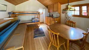 Una cabaña acogedora con literas, kitchenette y comedor.