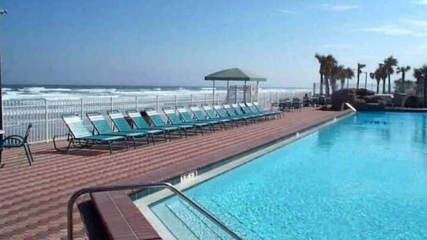 Ein Poolbereich mit Liegestühlen und Blick auf den Ozean.