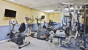 Ein Fitnessstudio mit verschiedenen Trainingsgeräten, darunter Laufbänder, Crosstrainer und Kraftgeräte.