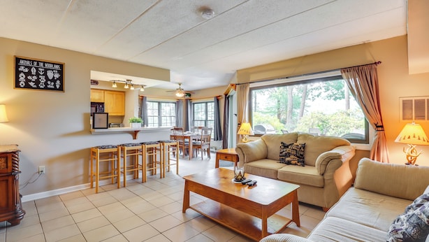 A living room with a sofa, coffee table, and dining area with chairs.