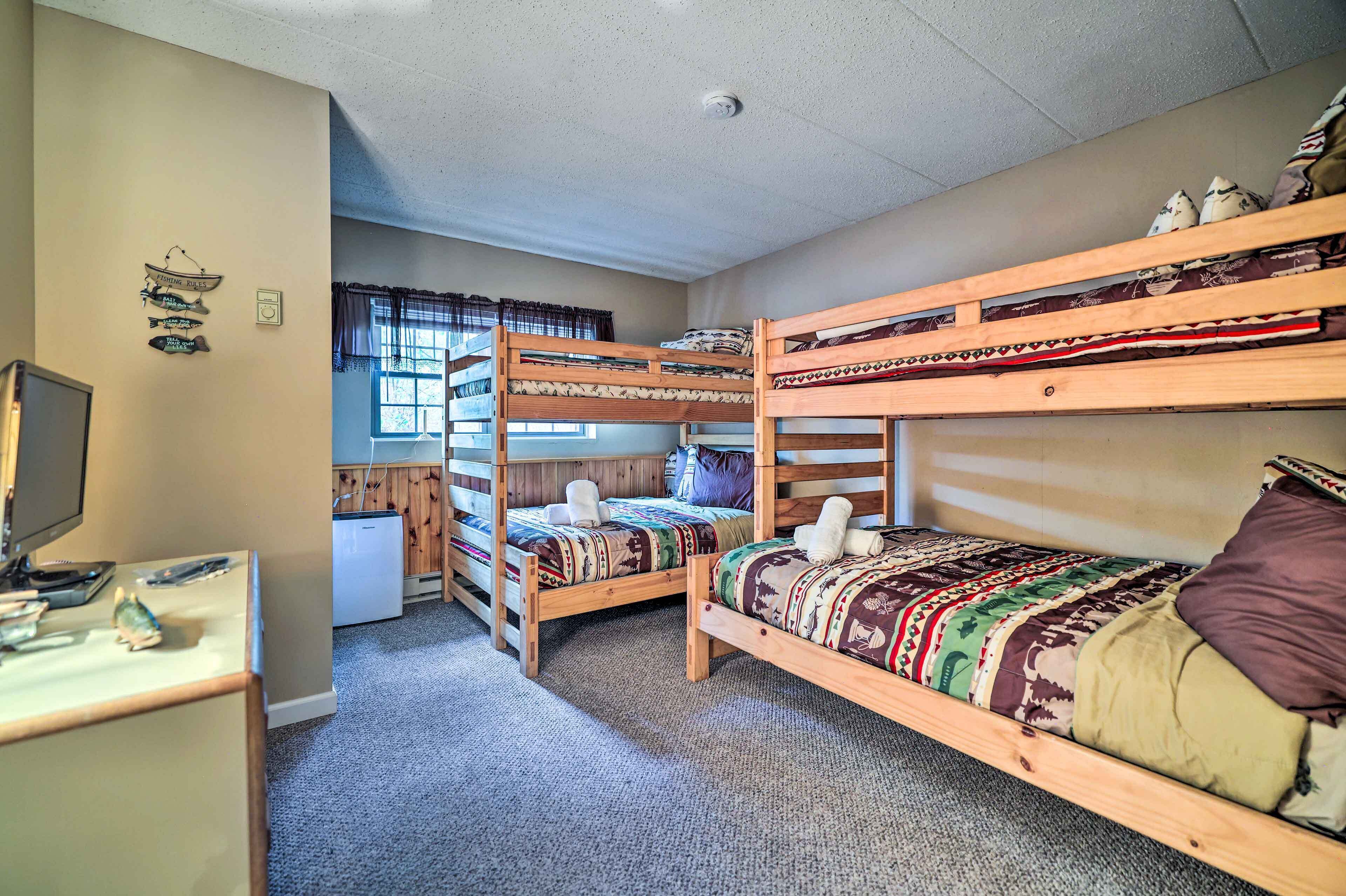 A dormitory room with bunk beds, a desk, a computer, and a window with curtains.