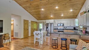 A spacious kitchen with wooden ceiling, white cabinets, and a central island with stools. - Hot Tub Relaxation & Mtn View: Sky Blue Overlook (Marble)