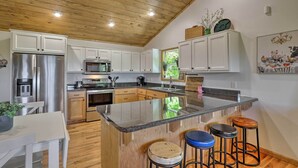 A modern kitchen with wooden cabinets, stainless steel appliances, and a central island with stools. - Hot Tub Relaxation & Mtn View: Sky Blue Overlook (Marble)