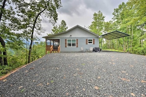 A house with a gravel driveway, wooden deck, and a covered patio area. - Hot Tub Relaxation & Mtn View: Sky Blue Overlook (Marble)