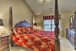 Quarto com cama de dossel, penteadeira e mesa de cabeceira.